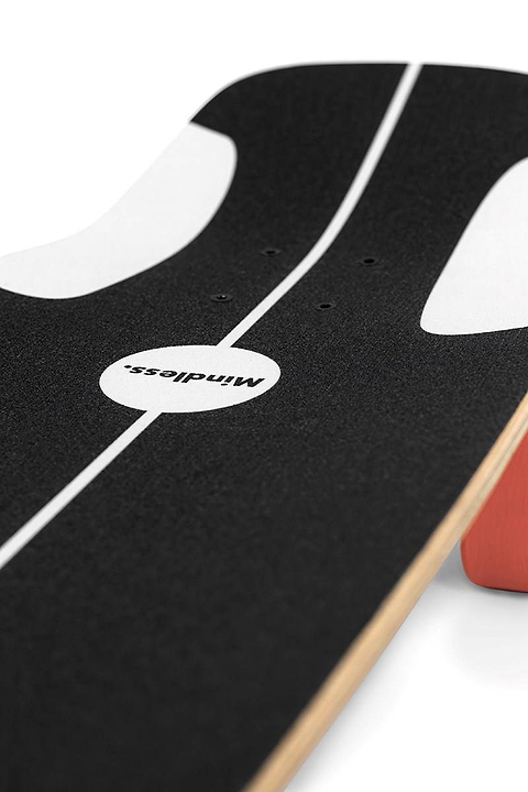 Close-up of the Mindless Soul Surf Skate Cruiser Skateboard 29.5″ x 9.75″ - Red with black grip tape, white accents, a center white line, “Mindless,” and an orange wheel visible on the right. Brand: Mindless.