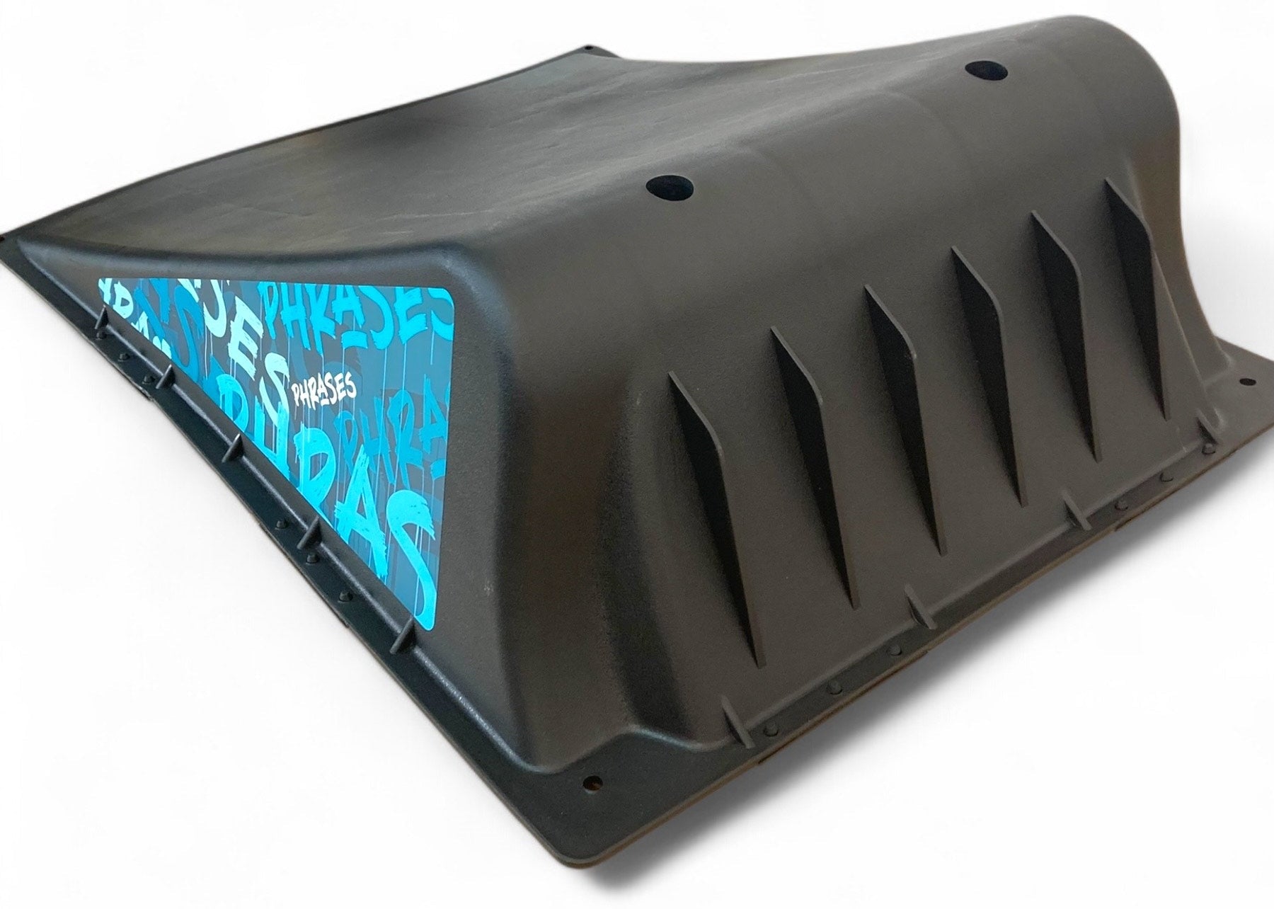 The Phrases One Way Kicker Skate Ramp by Phrases is a black plastic ramp with angled grooves and a blue section with white text, ideal for beginner skateboarders as a portable skate ramp, shown on a white background.