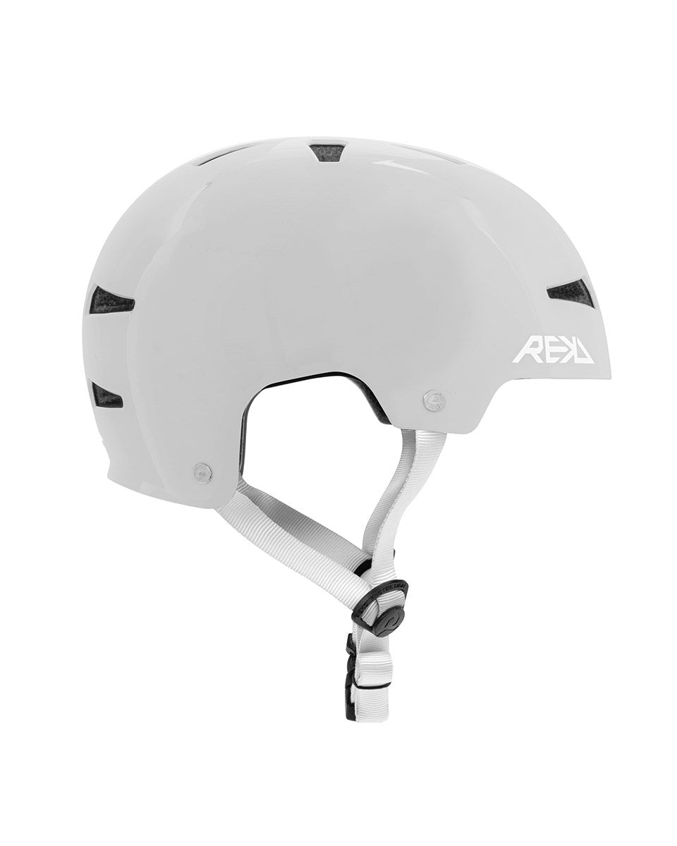 The REKD Elite 2.0 Skate / Scooter Helmet - Gloss Silver features black vents, an adjustable white chin strap, and the REKD logo. Certified for safety, it offers reliable protection and style, as shown in a side profile on a plain background.