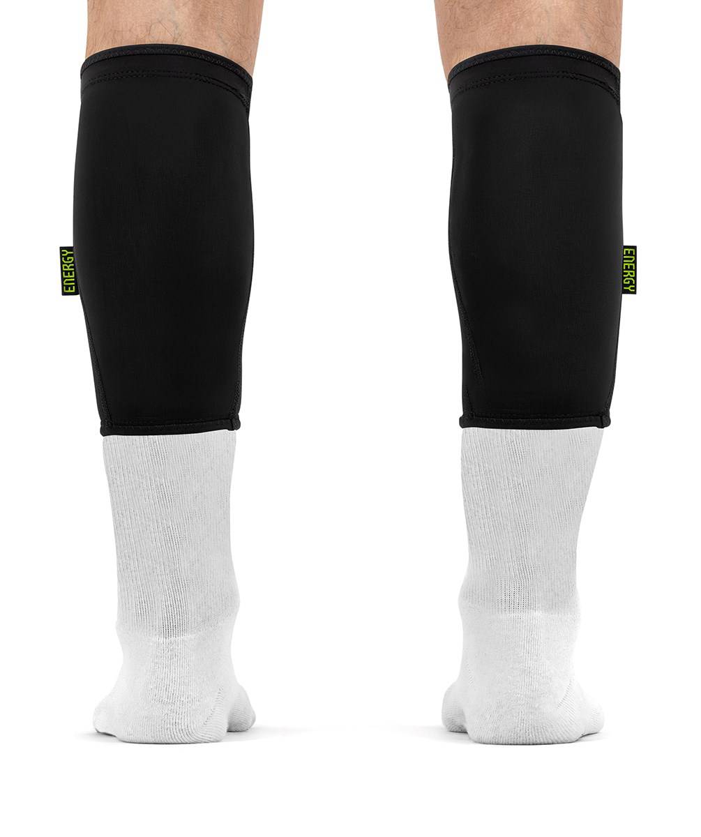 Black REKD Energy Covert Short Shin Skate Protection Guards worn for impact protection over white socks on a person’s lower legs.