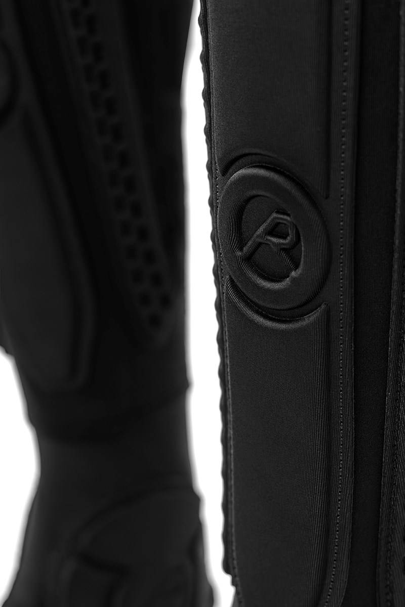 Close-up of a black REKD Energy Covert Long Shin and Ankle Skate Protection Guard featuring a circular logo embossed on the protective padding for essential ankle protection.