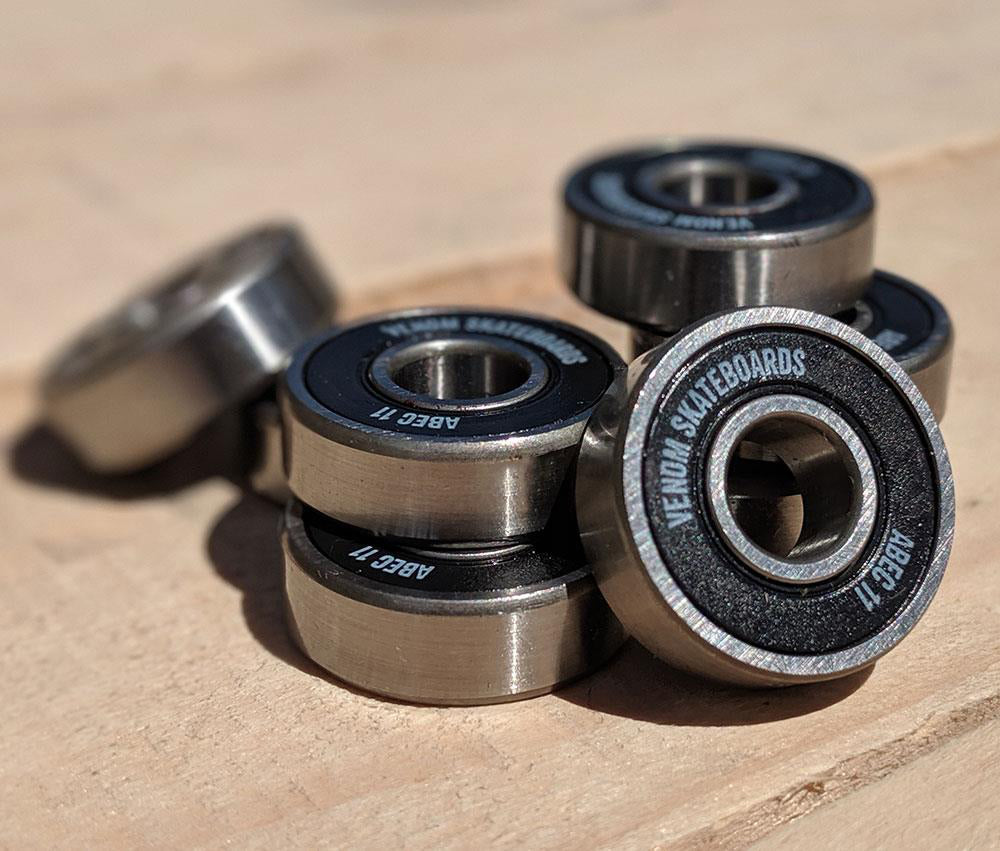 A small pile of Venom ABEC 11 Skateboard Bearings - 8 Pack featuring black rubber seals and silver metal rings.