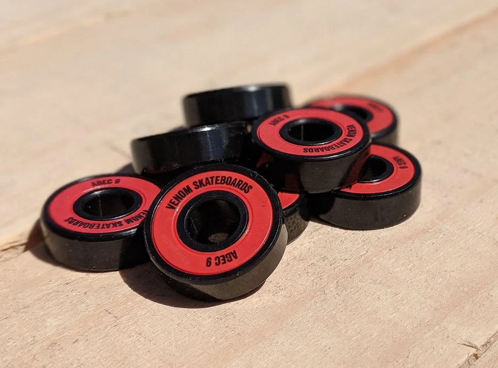 A pile of Venom ABEC 9 Skateboard Bearings - 8 Pack featuring black housings and red circular seals.
