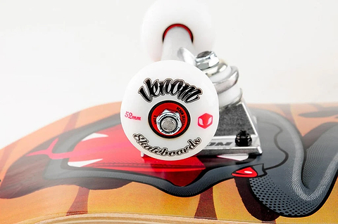 Close-up of a Venom Junior Desert Viper Kids Complete Skateboard - 7.25″ x 29″ deck featuring a graphic of a snake’s open mouth, showing a white wheel with black lettering and silver hardware.