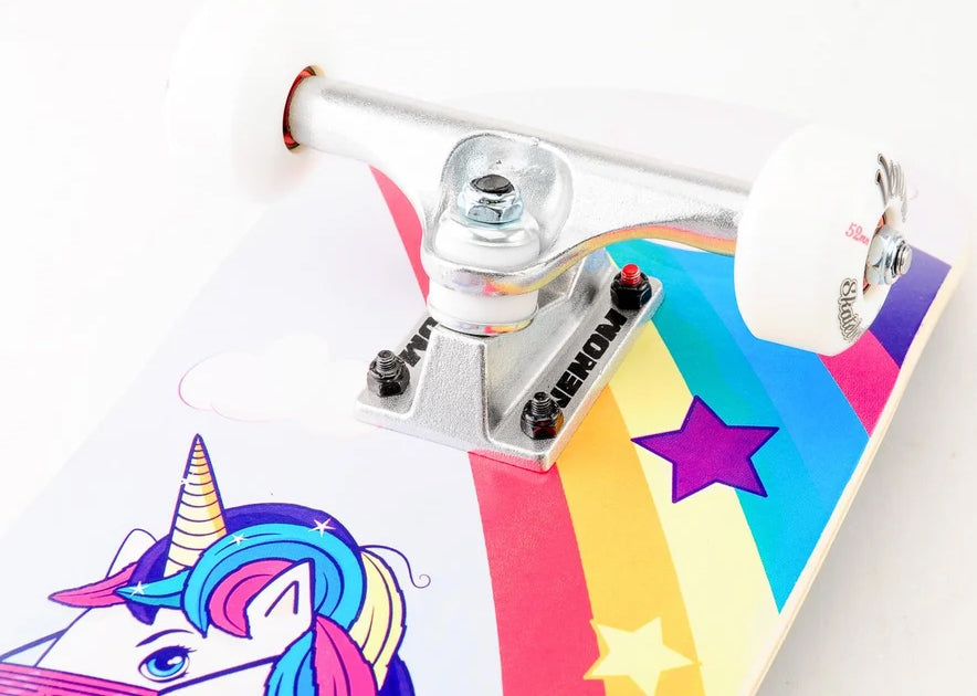 Venom Junior Unicorn Kids Complete Skateboard - 7.25″ x 29″ featuring a unicorn graphic, a rainbow stripe, and silver trucks with white wheels.
