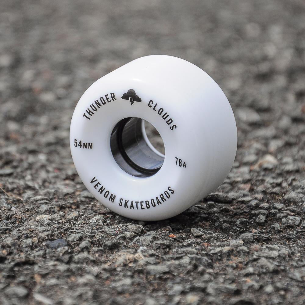 A white Venom Thunder Clouds V2 60mm 78A skateboard wheel printed with “54mm,” “78A,” and “Venom Skateboards” resting on asphalt.