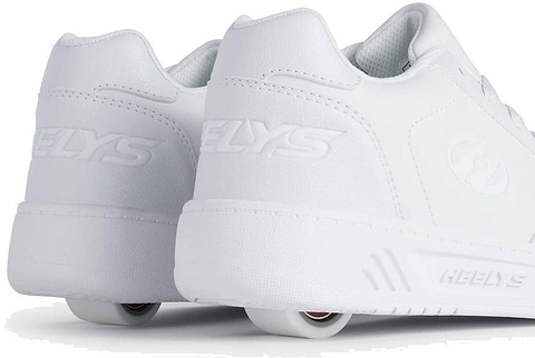 The Heelys Kama Girls Shoes in white feature low-profile wheels in the heels, blending classic court-style design with fun mobility. Shown from back and side views on a white background. Brand: Heelys.