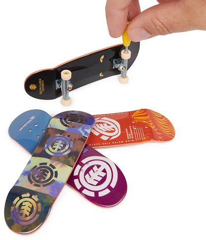 A hand uses a tool to adjust the wheels of a Tech Deck M01 Deluxe 4 Pack Fingerboards - Element by Tech Deck, with three colorful fingerboards featuring authentic graphics lying on a white surface below.