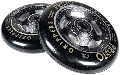Two black Proto Catalyst Gripper 110mm stunt scooter wheels by Proto, featuring silver and gray graphics plus "PROTO GRIPPERS" and "Performance Urethane" text on the outer edge, are stacked with a slight overlap.