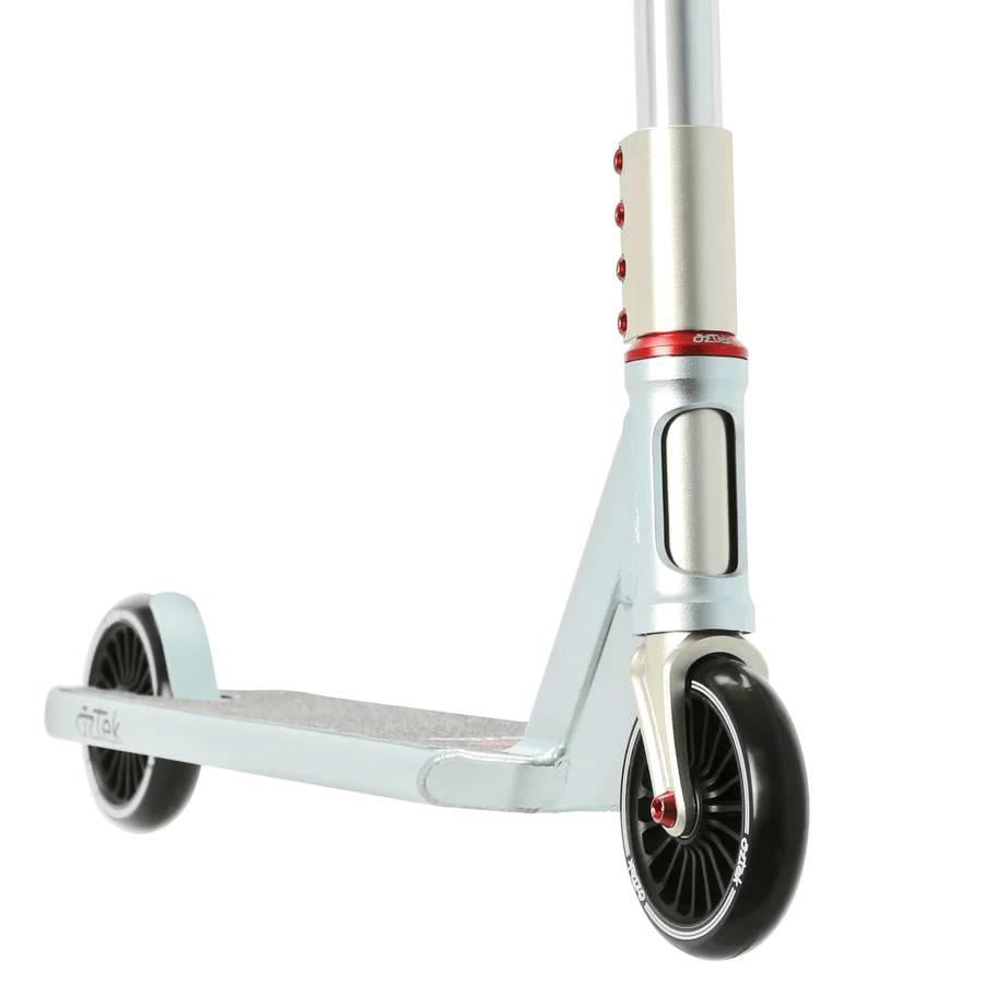 Close-up of the Aztek Corsa Complete Stunt Scooter in blue, featuring the deck, front and rear wheels, and lower handlebar with red accents. The lightweight Aztek scooter is angled on a white background.