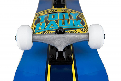 Close-up of the Tony Hawk SS 180+ Badge Logo Blue/Yellow Complete Skateboard (7.5" x 31") featuring bold yellow branding, white wheels, and a metal truck—an ideal Tony Hawk skateboard for beginners.
