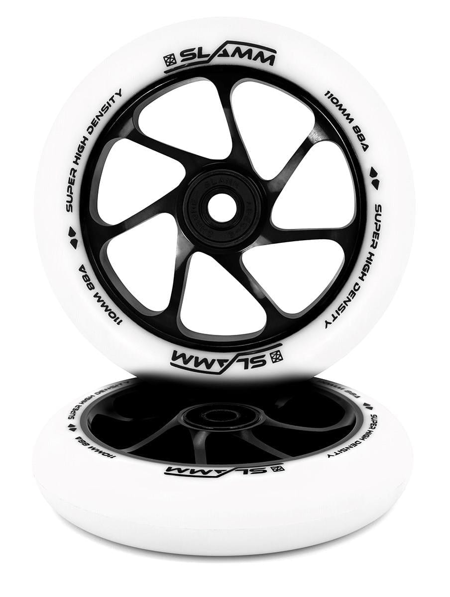 Two Slamm Team 110mm stunt scooter wheels feature a stylish black spoke design with white outer rims. The aluminium core enhances durability and showcases the "Slamm" branding alongside the "Super High Density" and "110mm 88A" specifications. Crafted with high-rebound PU construction, they offer excellent performance as one wheel elegantly rests against the other.