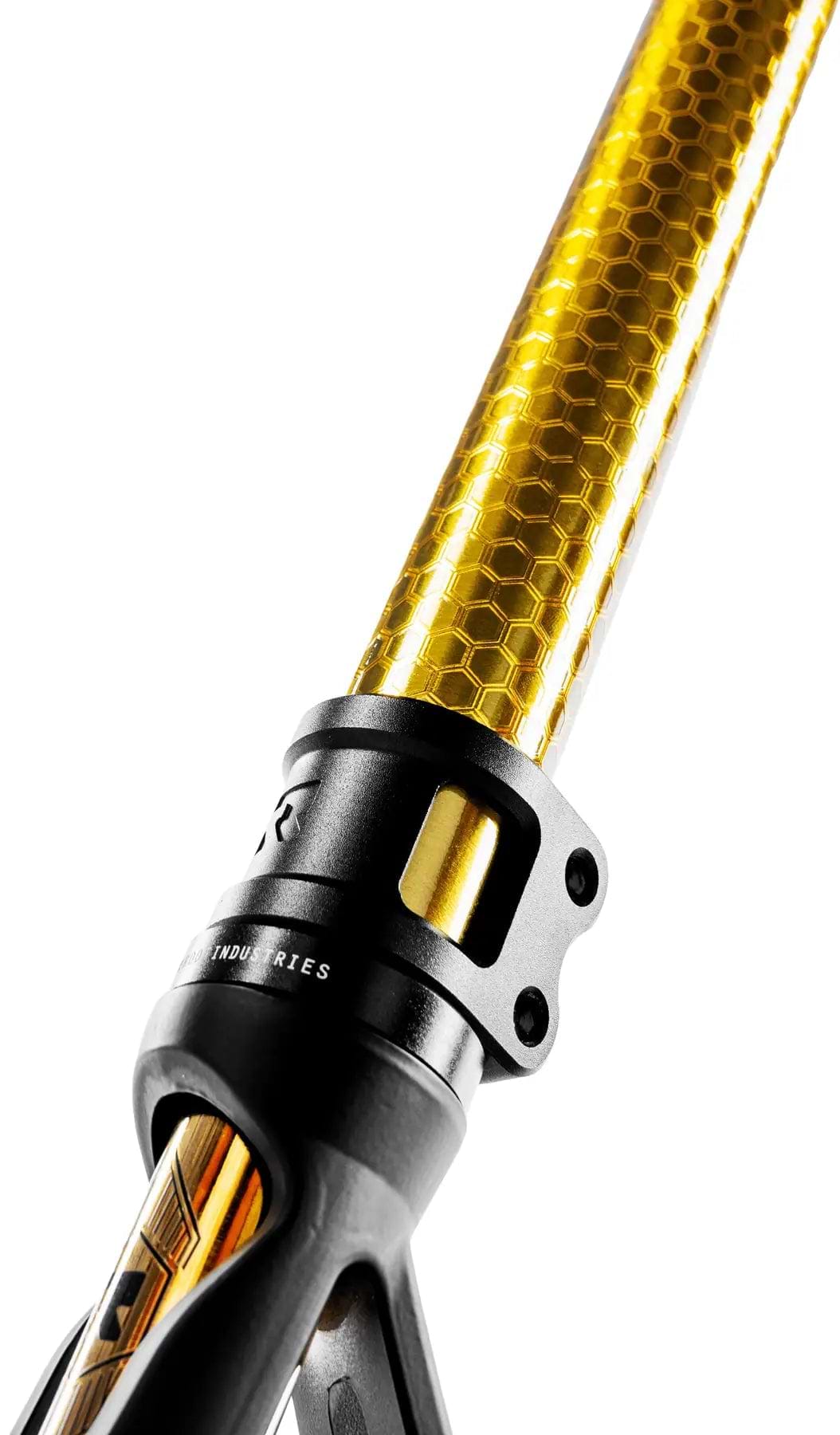 Close-up of a metallic object featuring a gold tube with a honeycomb pattern, similar to the Honeycore wheels on the Root Industries Invictus V3 Complete Stunt Scooter - Burnt Gold by Root Industries, attached to a black component with engraved text against white.