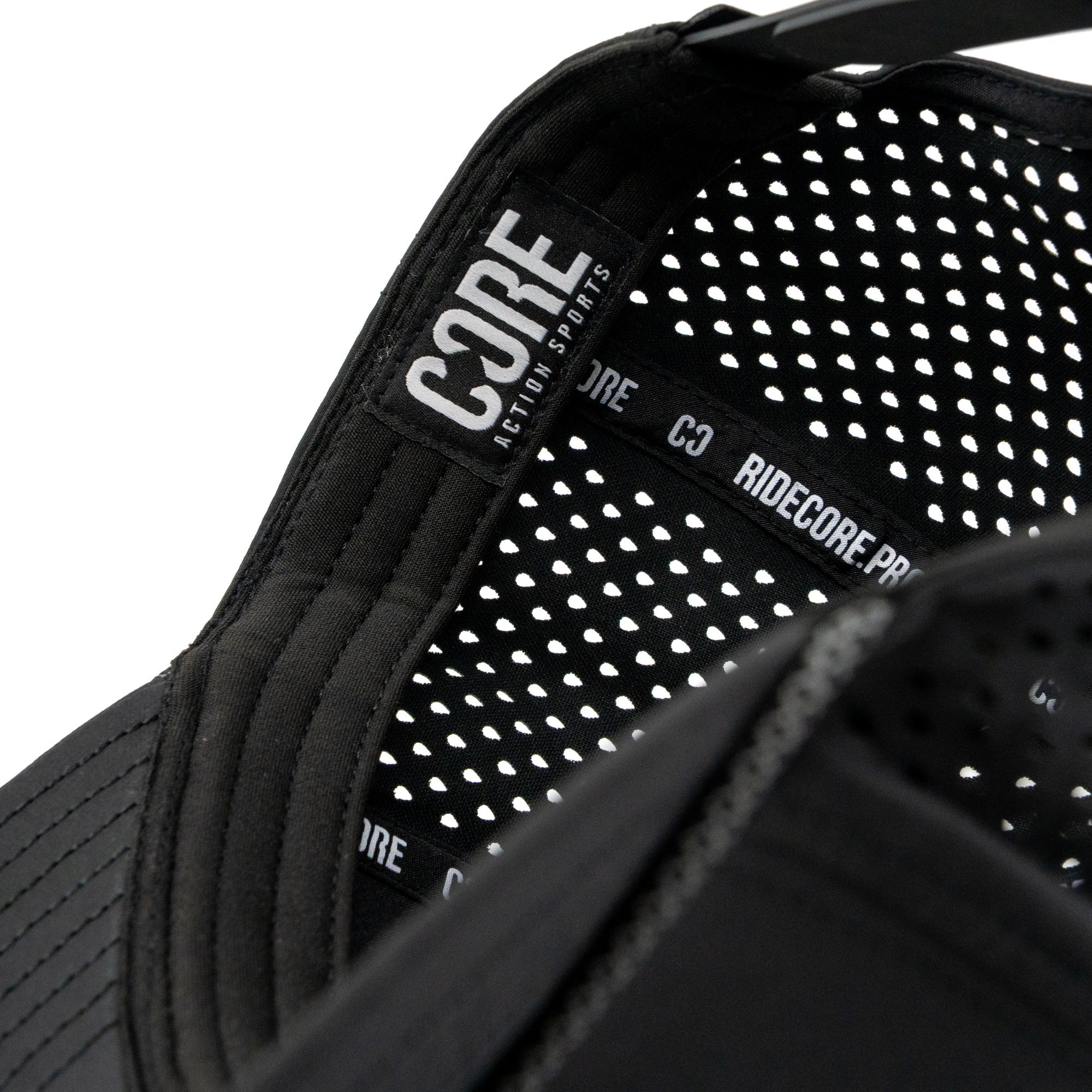 Close-up of the inside of the CORE Aero Rope Cap - Black, showcasing a signature CORE logo label and a patterned, perforated liner with “RIDECORE.PRO” text on the inner black band—attentive detailing that sets this premium performance cap apart.