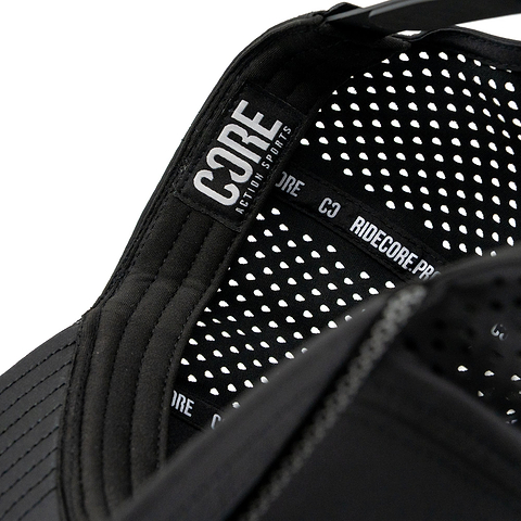 Close-up of the inside of the CORE Aero Rope Cap - Black, showcasing a signature CORE logo label and a patterned, perforated liner with “RIDECORE.PRO” text on the inner black band—attentive detailing that sets this premium performance cap apart.