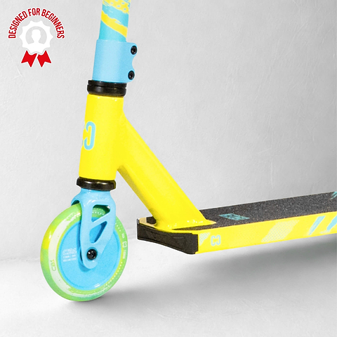 Close-up of the front wheel and deck of the CORE CB1 Beginner Complete Stunt Scooter in Highlighter Yellow and Blue, with a "Designed for Beginners" badge in the top left corner on a light gray background. This beginner stunt scooter by CORE is perfect for those just starting out.