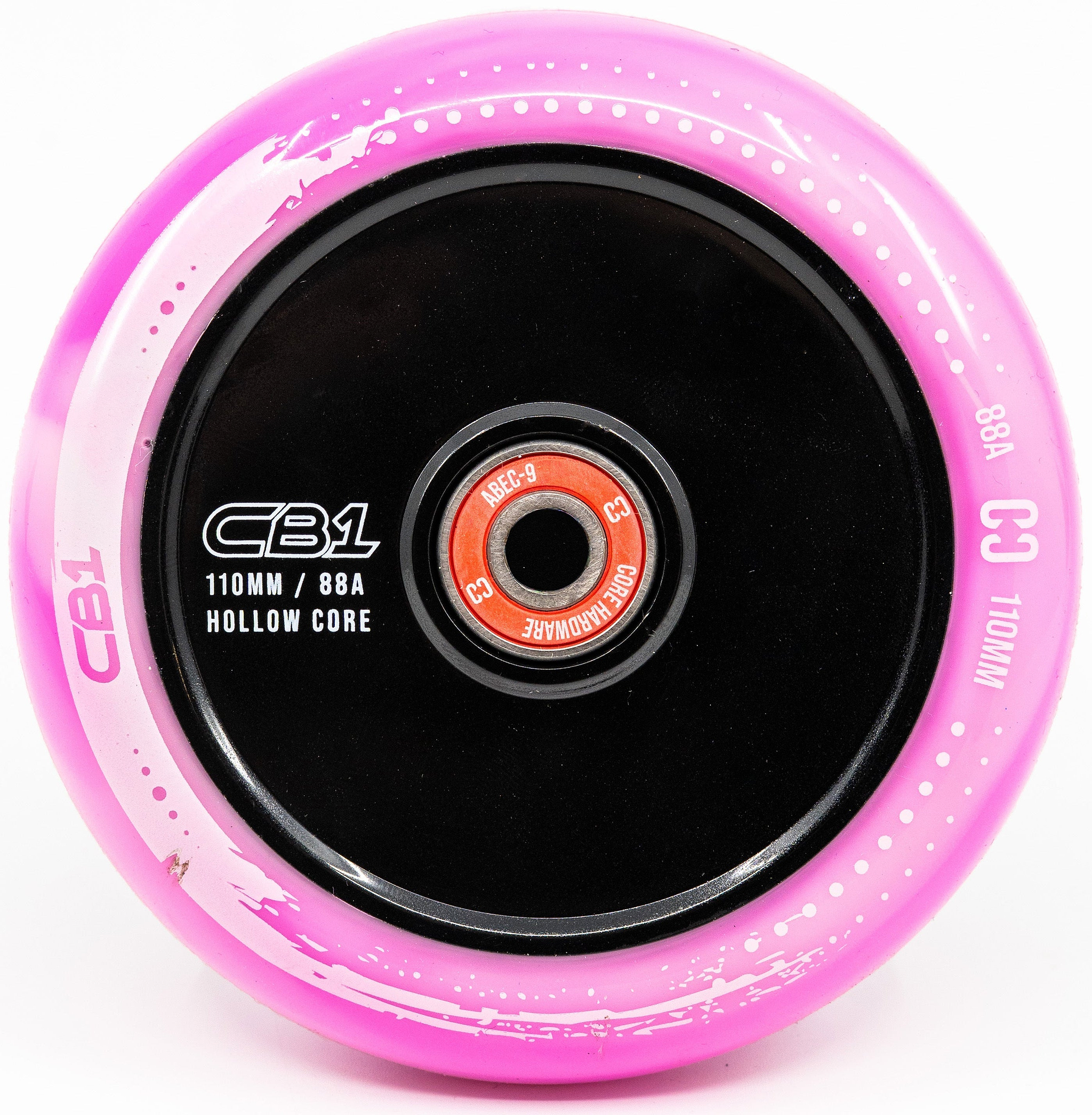 A close-up of the CORE CB1 110mm Nylon Scooter Wheel in White and Pink, featuring a black core and red bearing, with “CB1 110MM / 88A HOLLOW CORE” and “C3 110MM 88A” labeled along the rim. This durable CORE stunt scooter wheel is engineered for both performance and style.