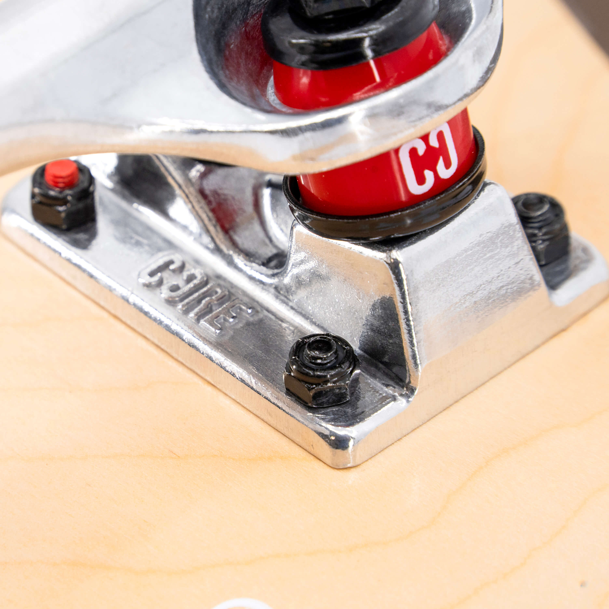 Close-up of a silver skateboard truck on a CORE C2 Pink / Blue Split Complete Skateboard - 7.75″ x 31″ maple deck, featuring red bushings and black mounting hardware.