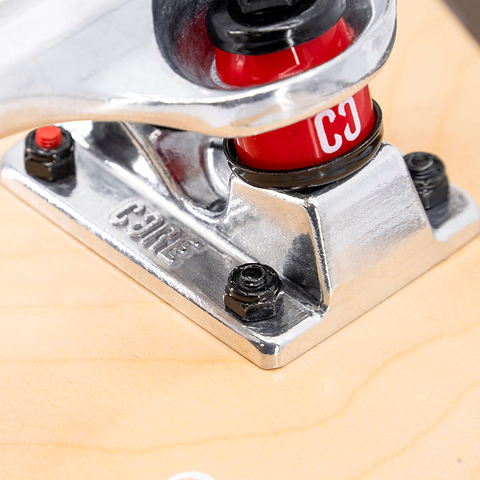 Close-up of a silver skateboard truck on a CORE C2 Pink / Blue Split Complete Skateboard - 7.75″ x 31″ maple deck, featuring red bushings and black mounting hardware.