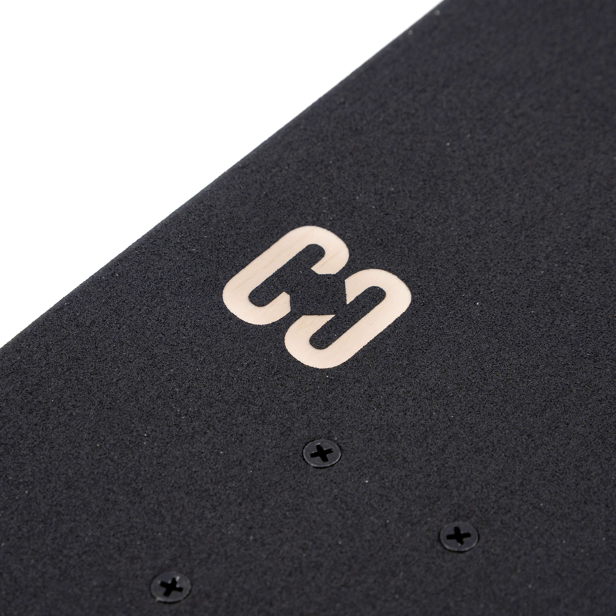 Close-up of the black grip tape on a CORE C2 Raw Split Complete Skateboard - 7.75″ x 31″ deck, featuring a gold logo and visible mounting hardware.