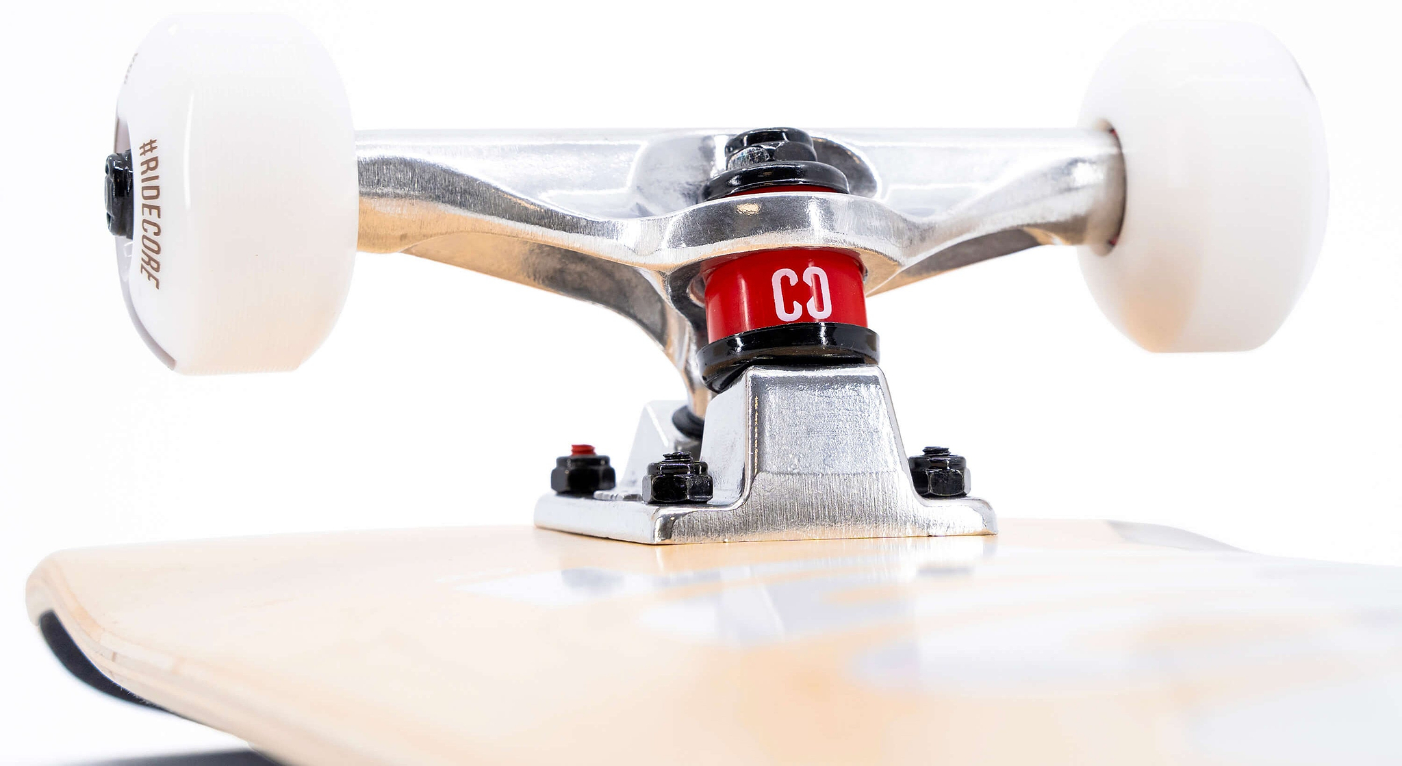 Close-up of a CORE C2 Raw Split Complete Skateboard 7.75″ x 31″ featuring white wheels attached to a wooden deck with a red bushing printed with “CO”.