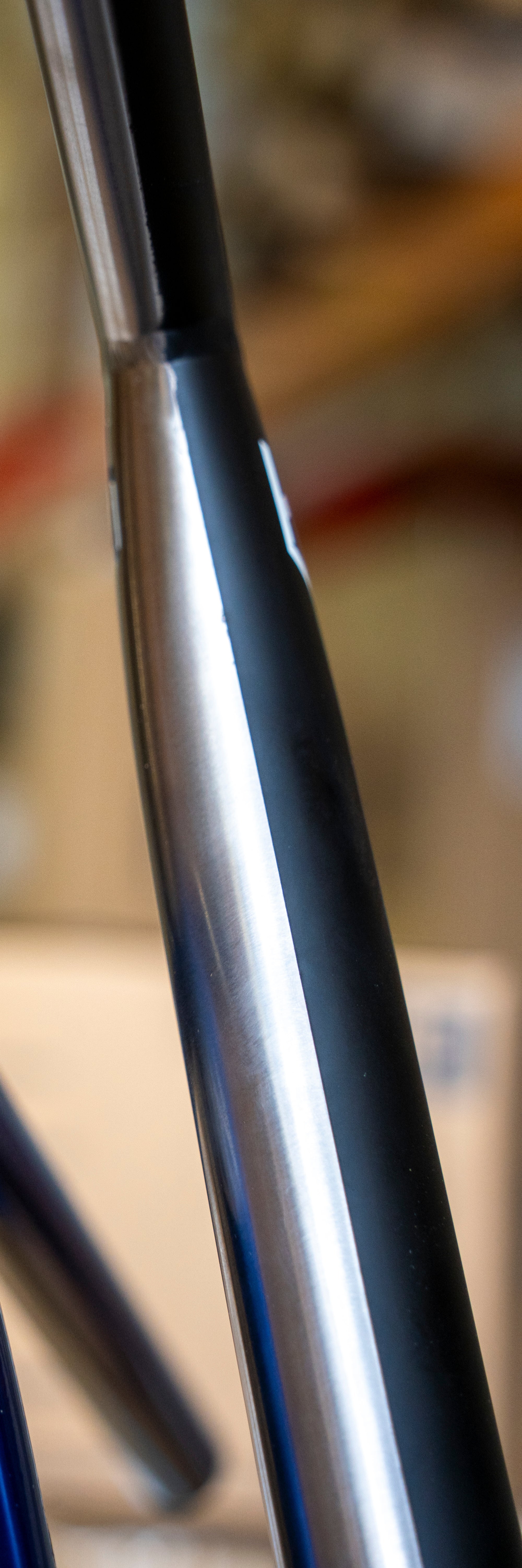 Close-up of CORE Halfbarz V2 Titanium Oversized HIC Stunt Scooter T-Bars with a split design, featuring a metallic chrome finish on one side and a matte black finish on the other.