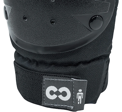 Close-up of a CORE Junior Triple Skate Protection Pad Set in black/grey, featuring a hard plastic shell and stitched fabric base. A small tag with CORE's white logo emphasizes skatepark safety for kids.