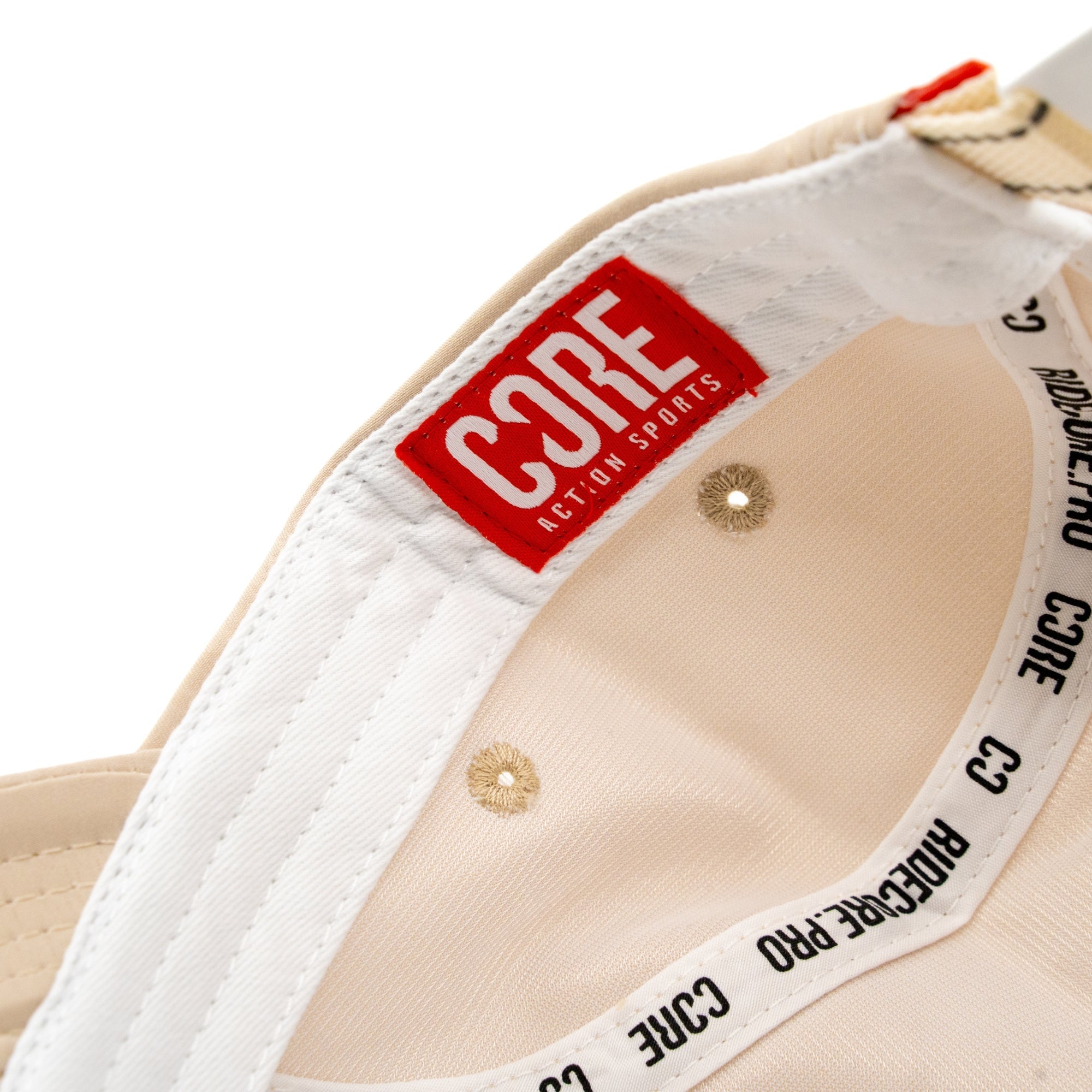 Close-up of the inside of the CORE Performance Cap - Sand / Reflective, featuring a red “CORE ACTION SPORTS” label and black “CORE PRO” text on the inner band. The breathable fabric by CORE ensures comfort during active use.