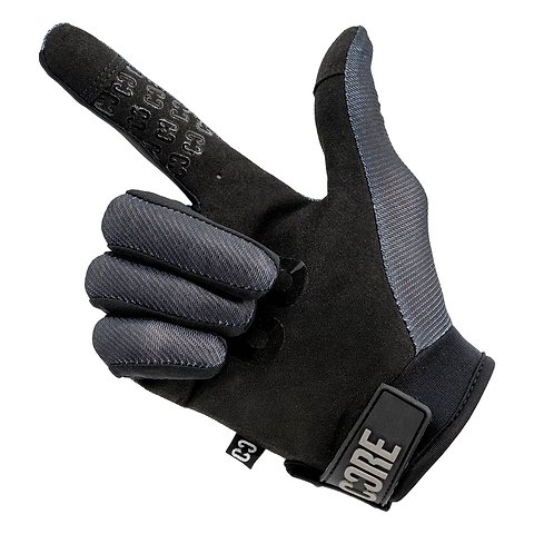 A pair of CORE Pro-Fit Velcro Skate Protection Gloves - Reflective Black by CORE is shown with the index finger pointing and the thumb extended, mimicking a hand gesture that resembles a gun or pointing. These black and gray gloves feature a reflective finish, display the CORE logo on the wrist strap, and are touch screen friendly—providing both style and functionality for riders.