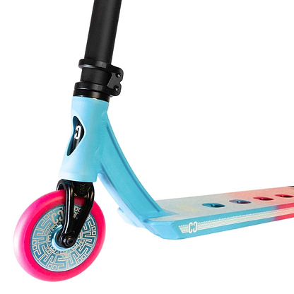 Close-up of the vibrant CORE CL1 Complete Stunt Scooter by CORE, focusing on the front pink wheel with its distinctive geometric design and the deck featuring a striking blue-to-red gradient, complete with a logo and multiple cut-out holes. Experience seamless integration with premium aftermarket parts for an unparalleled ride.