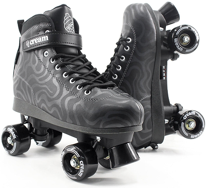 A pair of CREAM Scoop Wave Adjustable Quad Roller Skates in black, featuring vegan leather construction with a wavy gray pattern, black laces, and “CREAM” branding on the strap and wheels. Perfect for beginners, one skate is displayed upright while the other rests on its side to showcase the wheels.