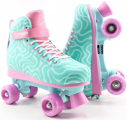 The CREAM Scoop Wave Adjustable Quad Roller Skates in teal and pink feature wavy patterns, pastel pink wheels, and signature CREAM branding. Designed for beginners, these high-top skates include laces and a velcro strap, making them perfect adjustable quad roller skates for those just starting out.