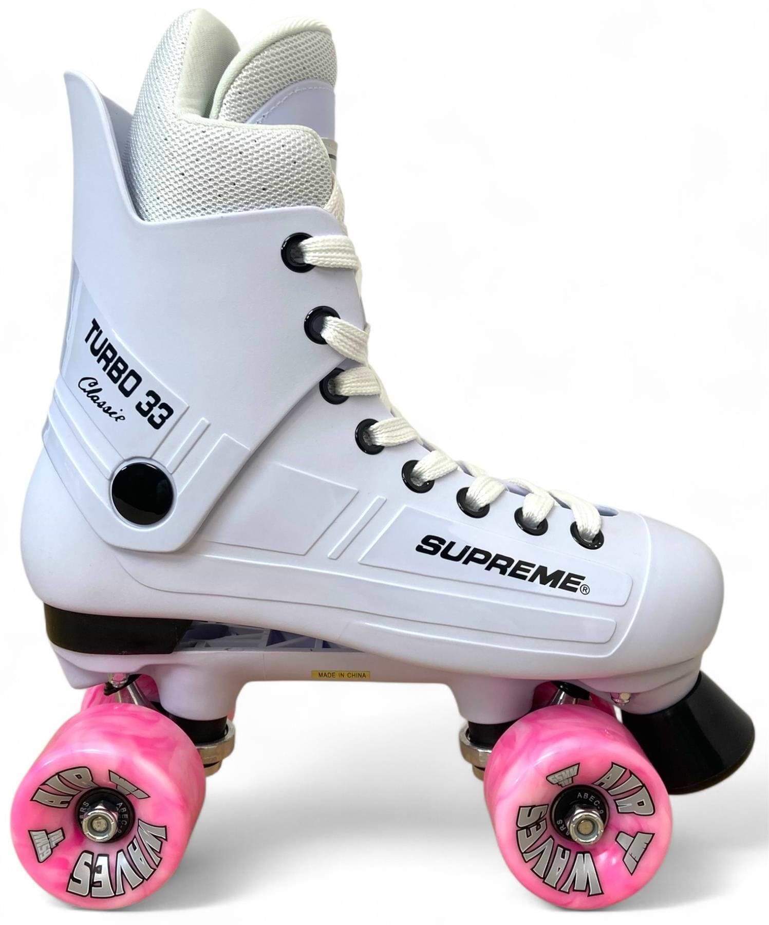 The Supreme Turbo 33 Nylon Quad Roller Skates feature a white boot with black accents, pink swirl wheels, and white laces. The stylish skates display the Supreme brand and stand out against a clean white background.