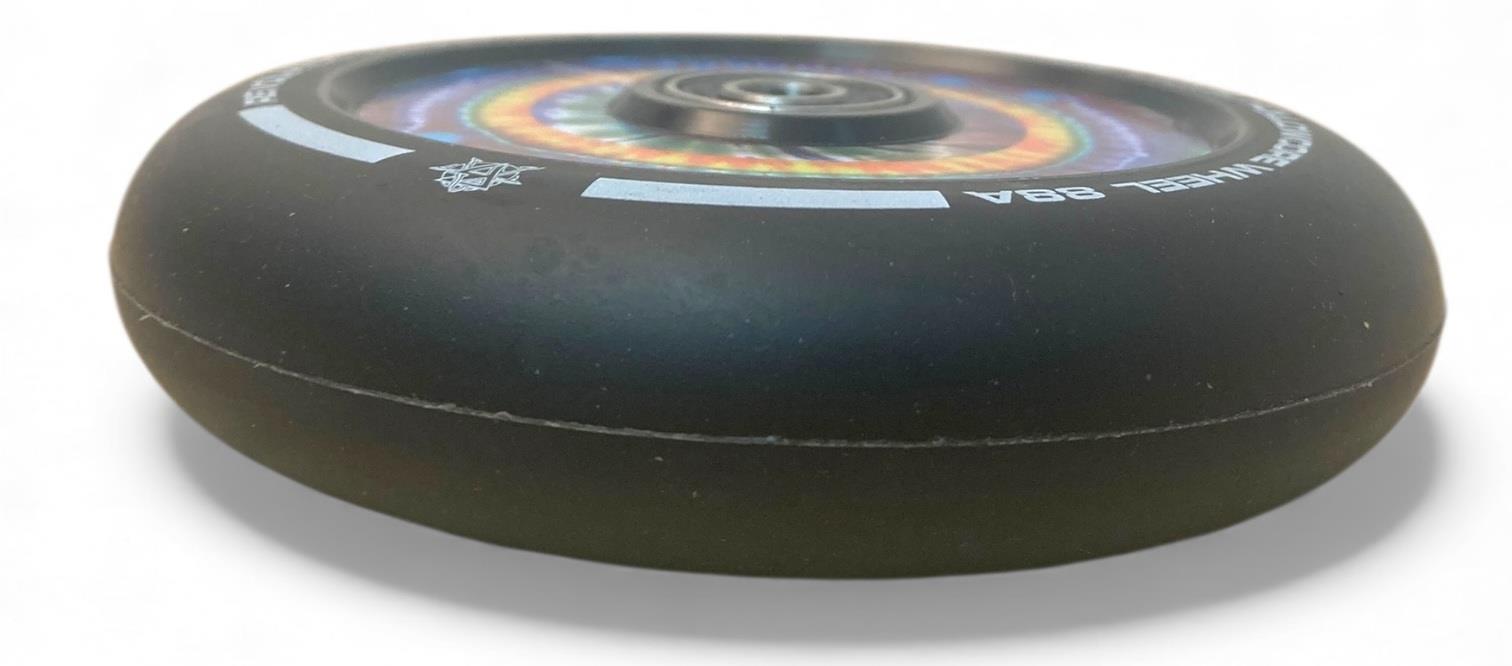A close-up of the Revolution Hollowcore 110mm Stunt Scooter Wheel—Spanner Jones Signature—by Revolution, featuring a black design, ABEC 9 bearing, and rainbow hub pattern, shown on a white background.