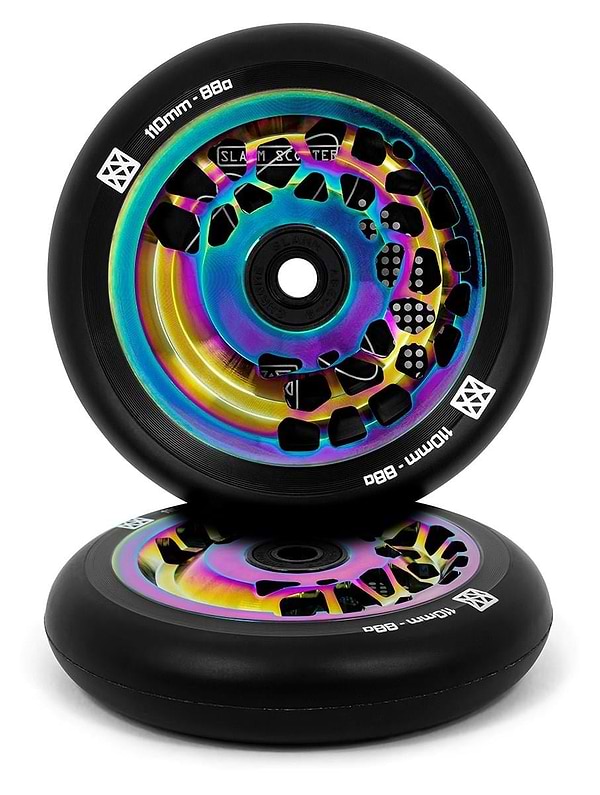 A pair of eye-catching Slamm Split Core 110mm stunt scooter wheels features a colorful neochrome finish with an iridescent core, showcasing contrasting designs on black rubber. The edges display "110mm Split Core - 88a" alongside the Slamm brand logo. One wheel rests against the other.