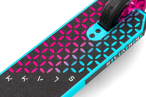 Close-up of the Slamm Assault Complete Stunt Scooter - Blue, showcasing its vibrant alloy deck adorned with a geometric pattern in pink and blue. The partially visible word "Kryptic" is featured on the side, accompanied by sleek 110mm aluminum wheels for smooth rides.
