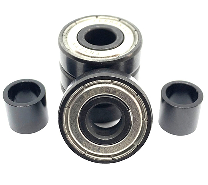 Close-up of a selection from the Entity Ceramic Scooter Bearings - 4 Pack. Two of these high-end bearings are ceramic and encased in sleek black cylindrical spacers, while three others are stacked, revealing their metallic inner rings and dark outer casings against a plain white background.