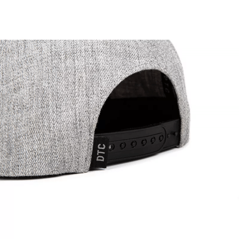 Close-up of the back of the Ethic DTC Snapback Cap in Deerstalker Grey, showcasing its classic snapback design. It features an adjustable black strap with multiple holes for size customization and a small black tag adorned with white "DTC" lettering near the strap, beautifully complemented by the embroidered Ethic logo on the side.