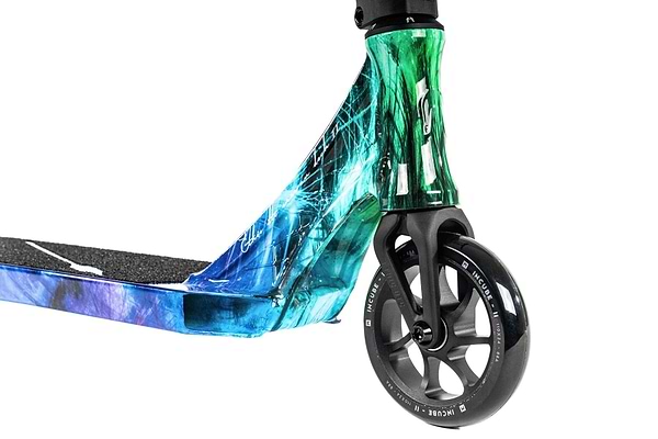 A detailed view of the vibrant and lightweight Ethic DTC Erawan V2 Complete Stunt Scooter (M) - Blue Iridium, highlighting the front wheel and deck adorned with a stylish pattern in shades of blue, green, and black. The wheel features a silver rim with "River" branding.