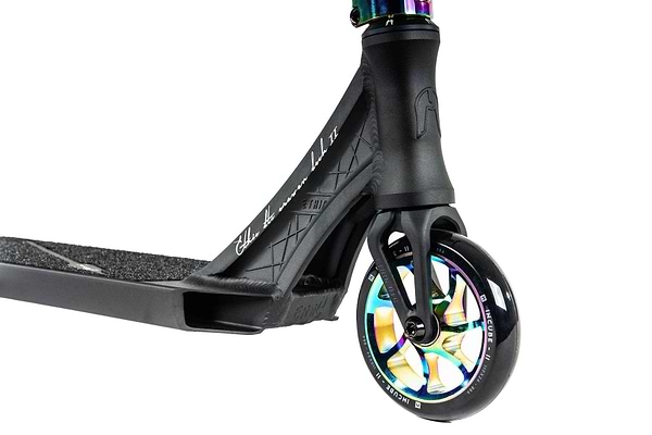A detailed view of the Ethic DTC Erawan V2 Complete Stunt Scooter (S) - Neochrome highlights its front wheel and deck. The wheel sports a vibrant, iridescent design, while the deck is equipped with a textured grip and branding. The fork and neck are sleek and robust, featuring IHC compression for enhanced performance.