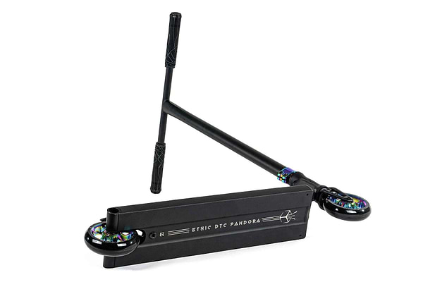 The Ethic DTC Pandora Complete Stunt Scooter (M) in Neochrome is a stylish freestyle scooter with a sleek black finish, featuring a flat deck branded "Ethic DTC Pandora." It comes equipped with two small wheels that have iridescent accents and a T-shaped handlebar with black grips, all set against a plain white background.
