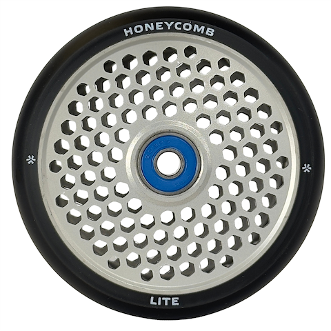 A close-up of the Union Honeycomb Lite 110mm Stunt Scooter Wheel by Union, featuring a silver honeycomb-patterned core, blue bearing, black rubber edges, and "HONEYCOMB" and "LITE" text on the rim.