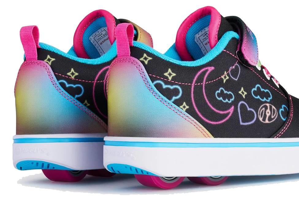 The Heelys Pro 20 Prints X2 Girls Shoes by Heelys feature colorful wheels in the soles, rainbow gradients, and fun hearts, stars, clouds, and moons on a black base with hot pink and multi-color accents.
