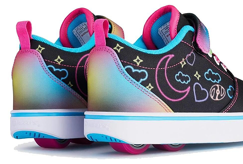 The Heelys Pro 20 Prints X2 Girls Shoes by Heelys feature colorful wheels in the soles, rainbow gradients, and fun hearts, stars, clouds, and moons on a black base with hot pink and multi-color accents.