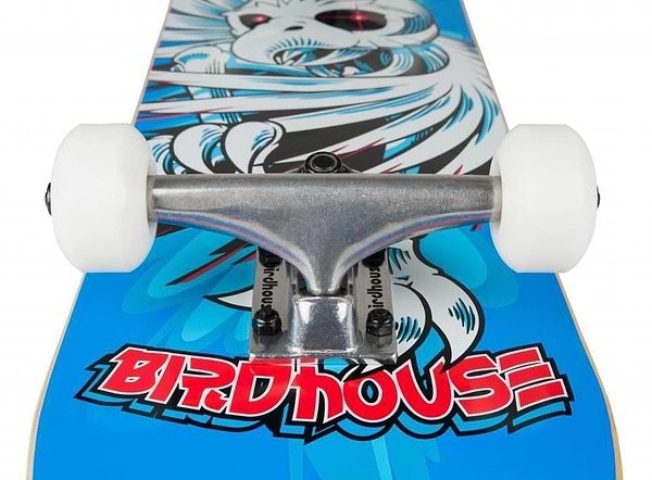 Close-up view of the Birdhouse Stage 1 Hawk Spiral Blue Complete Skateboard, featuring a metal truck and white wheels. The deck displays a vibrant graphic of a bird-like creature on a blue background, with "BIRDHOUSE" prominently written in red letters, making it ideal for both beginners and experienced riders.