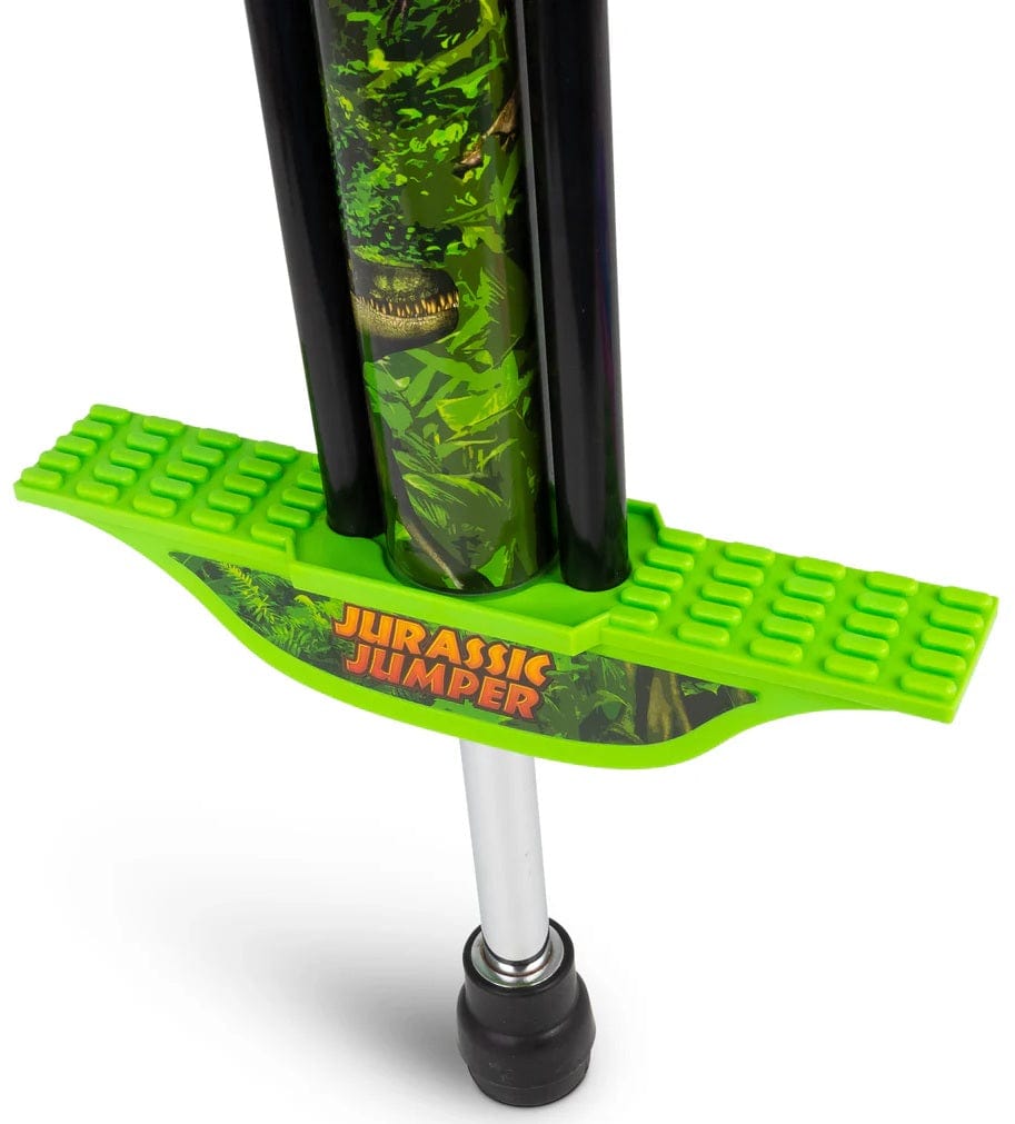 Close-up of the Ozbozz Dinosaur Kids Pogo Stick - Green, featuring chunky design, textured footrests, "Jurassic Jumper" in bold letters, a jungle motif with a dinosaur face—perfect pogo stick for kids by Ozbozz.