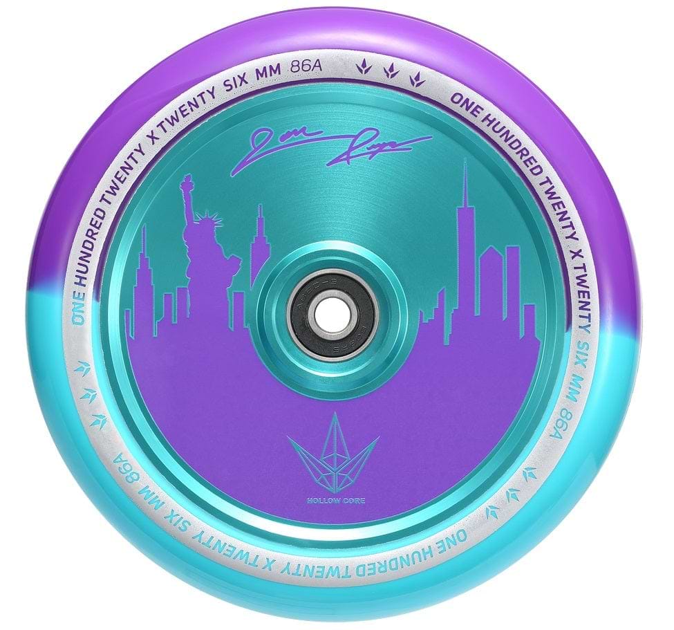 Introducing the Blunt Envy 120mm Jon Reyes Signature Hollow Core Stunt Scooter Wheel in a striking purple core, beautifully depicting a city skyline complete with the Statue of Liberty and towering skyscrapers. The outer rim features an eye-catching blue-to-green gradient. This wheel is expertly crafted with Blunt Envy's Hollowcore Technology and displays "ONE HUNDRED TWENTY SIX MM 86A" along its edge.