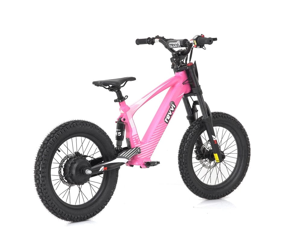 A pink Revvi 18" Kids Electric Balance Bike features thick black tires, black handlebars, and hydraulic disc brakes. The streamlined frame is designed with foldable MX-style foot pegs for added convenience. The rear suspension ensures a smooth ride while the Revvi brand name prominently stands out on the frame.