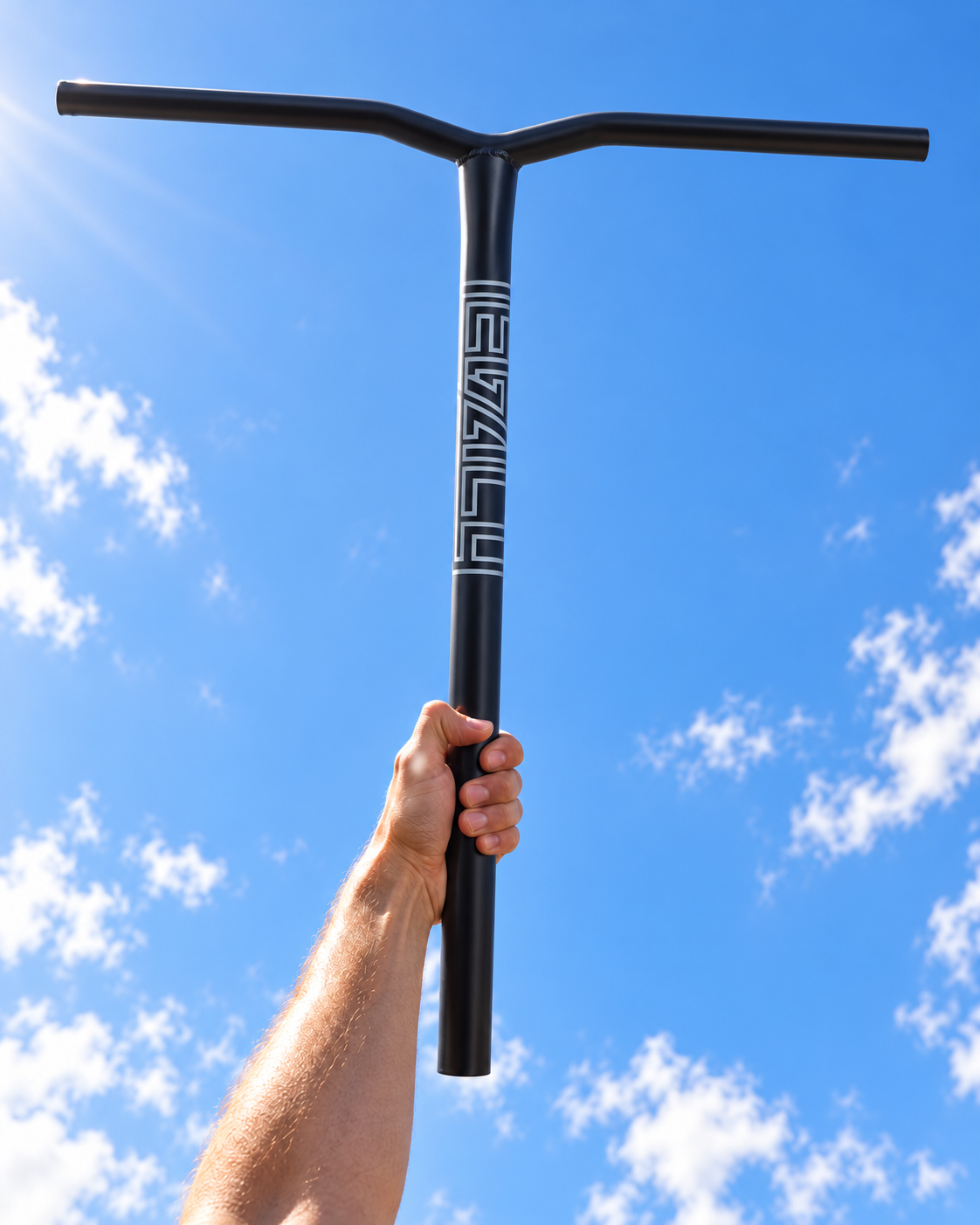 A hand holds black Legacy Ventus Steel Standard IHC Stunt Scooter Bars vertically against a bright blue sky with scattered clouds.