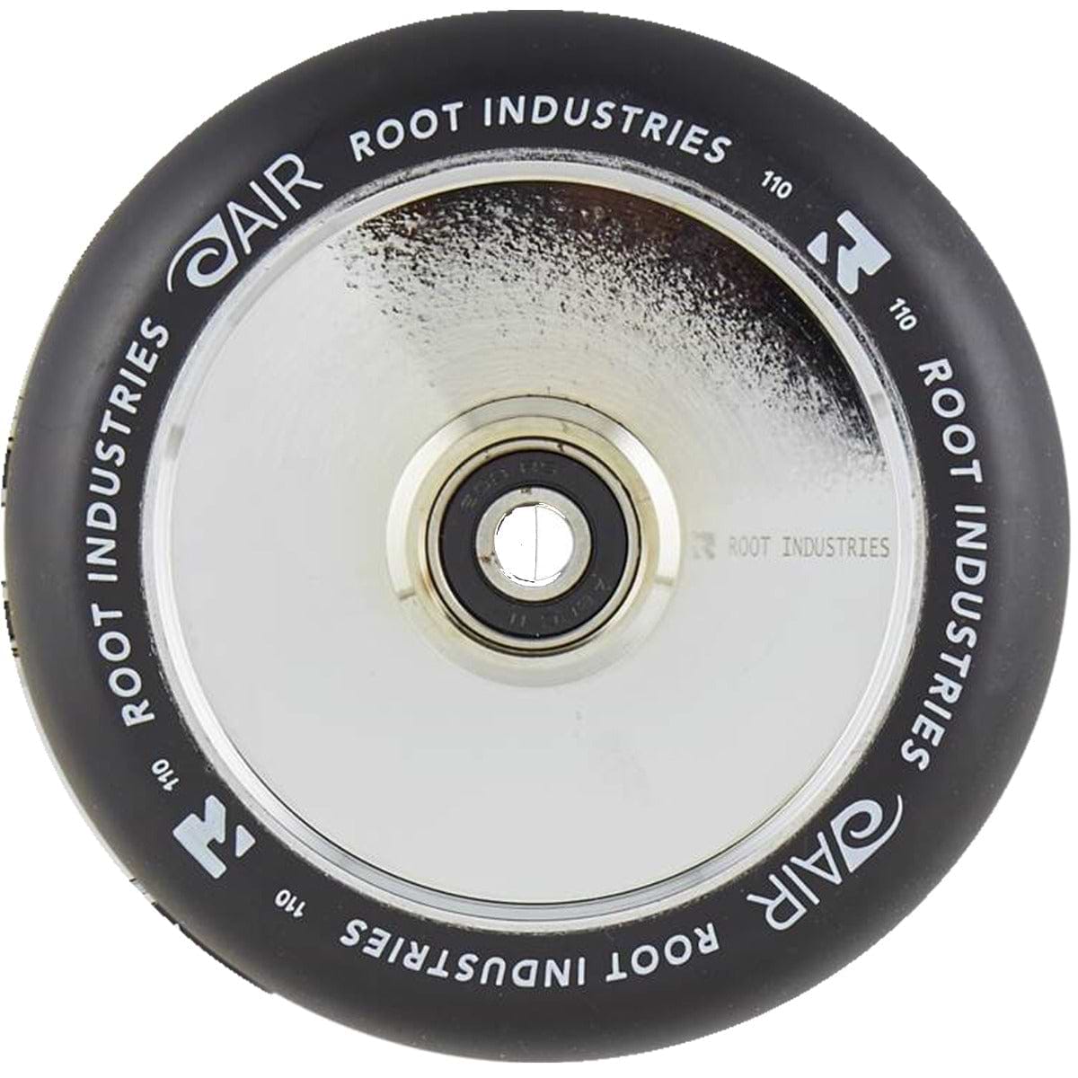A close-up of the Root Industries AIR Hollowcore 110mm Stunt Scooter Wheel from Root Industries shows off its striking mirror chrome silver core. The wheel's black tire is adorned with white branding text along the edge, and a central bearing facilitates easy attachment.